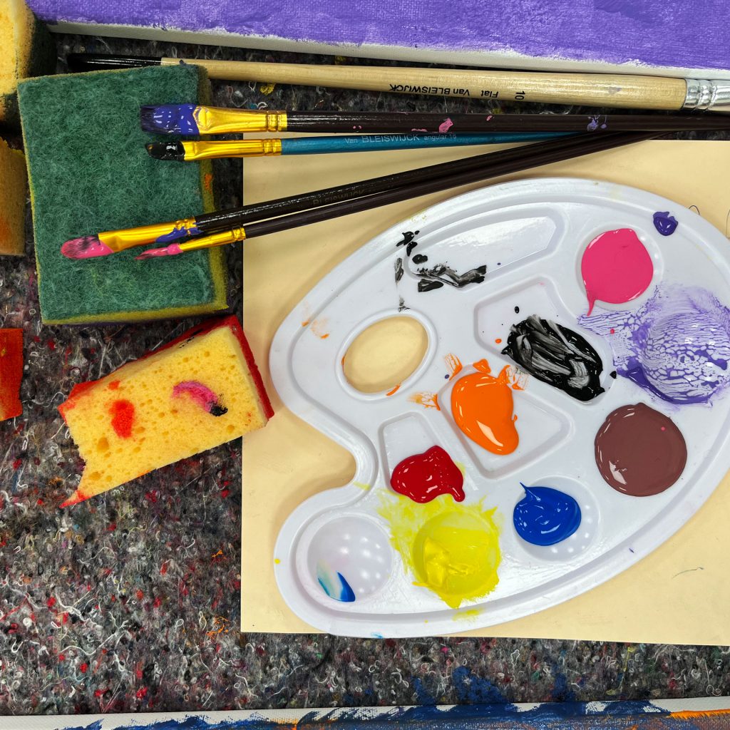 Pinsel und Farbpalette mit bunten Farben im offenen Atelier