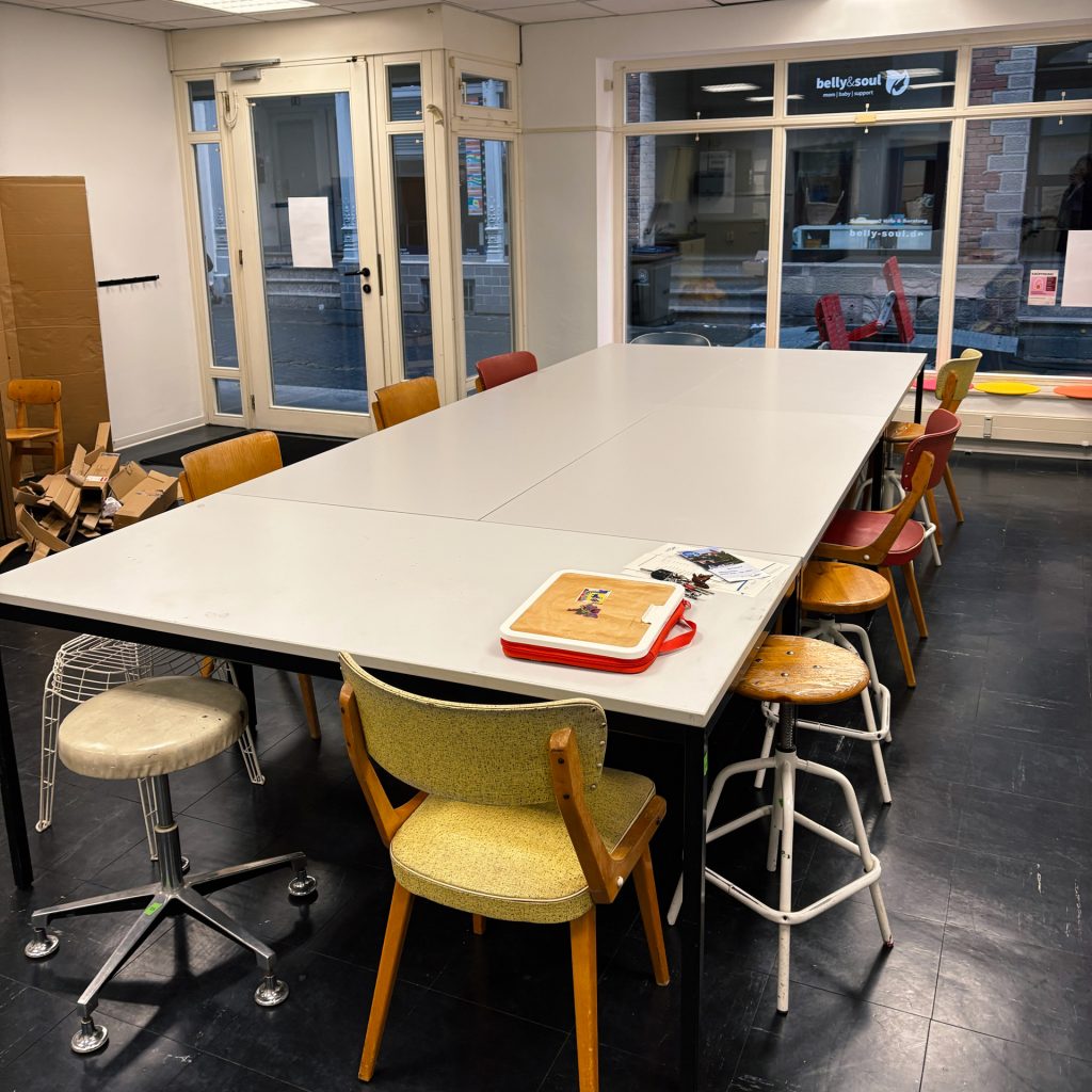 Nahaufnahme des Tisches mit bunten Stühlen aus Holz und Metall rundherum.